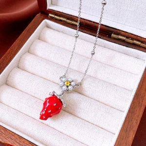 Detail of strawberry pendant necklace with pearls and crystals in a wooden jewelry box