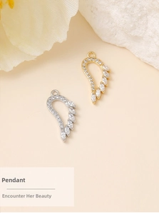 Detailed view of gold and silver angel wing pendants with inlaid zircon on a mineral stone