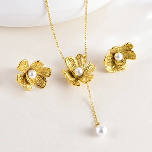 Vintage gold flower and pearl fringe necklace and earring set on minimalist background