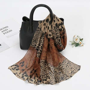 Detail of leopard print chiffon scarf draped over a black leather handbag in a chic setup