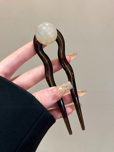 Détail d'une épingle à cheveux en U en résine marron avec une perle blanche ronde