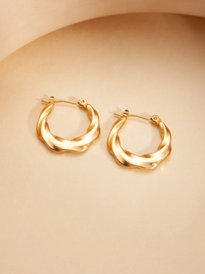 Detail of gold-plated titanium steel hoop earrings with a stylish twisted texture design