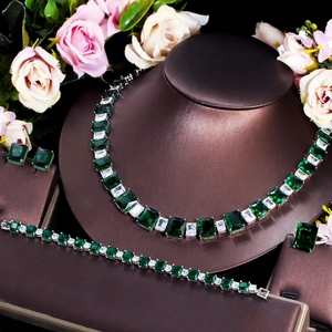 Parure bijoux mariée 4 pièces avec pierres vertes sur présentoir en velours marron