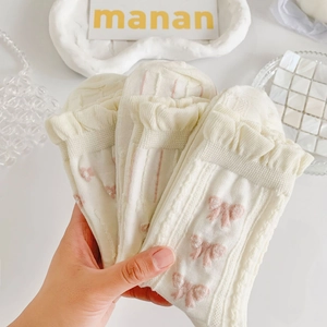 Detail of cream white lace socks with pink bow patterns and ruffled cuffs for women