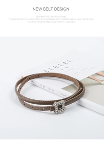 Detail of slim brown leather belt for women featuring a sparkling rhinestone square buckle