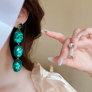 Makroaufnahme von mehrstöckigen smaragdgrünen Harzohrringen am Modell für elegantes Styling