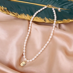 Close-up of natural freshwater pearl necklace with star-set gold pendant on silk fabric