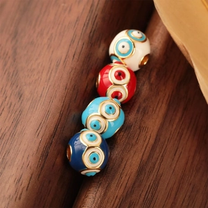 Macro shot of colorful enamel evil eye beads with gold plating on a wooden background