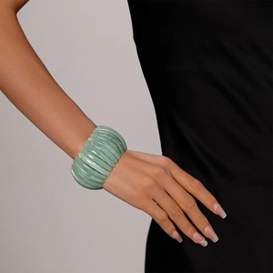 Gros plan d'un bracelet géométrique en acrylique vert clair sur le poignet d'un mannequin