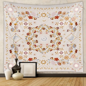Detail of bohemian tapestry featuring sun, moon, and floral motifs on a neutral wall