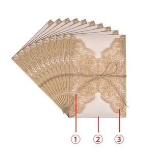 Golden laser-cut wedding invitations with floral lace patterns and rustic twine bows