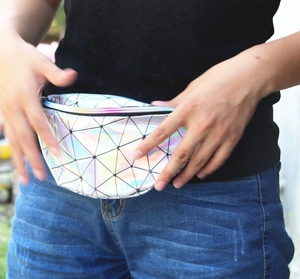 Close-up of geometric holographic waist bag worn on blue jeans with rainbow zipper detail