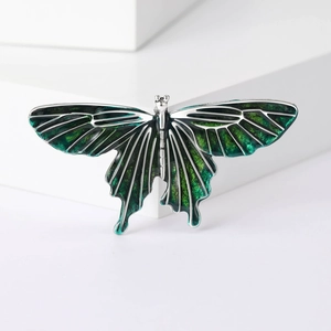 Detailed close-up of butterfly brooch with green gradient enamel inlay on silver base