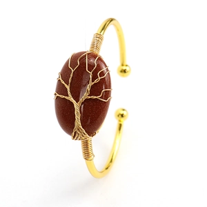Detail of tree of life wire-wrapped gold bracelet with brown goldstone gemstone