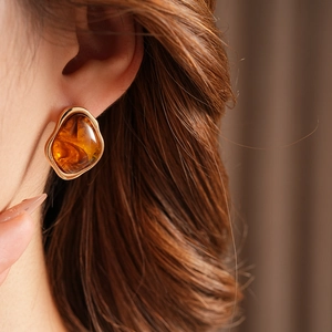 Close-up of vintage geometric resin earring with gold metal frame worn by a model