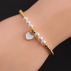 Detail of white pearl and gold bead stretch bracelet with a heart enamel charm on wrist