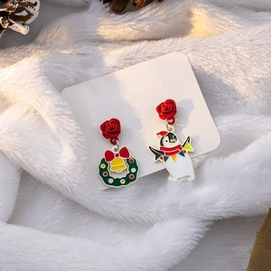 Detail of Christmas earrings featuring a festive wreath, jingle bell, and cute penguin