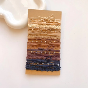 Detail of assorted woven hair ties with beads and bows in earthy tones on kraft card
