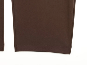 Detailed close-up of dark brown curved trousers showing twill fabric and hem stitching
