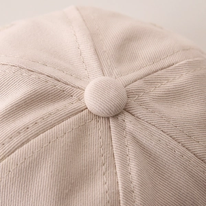 Dettaglio del bottone superiore e delle cuciture in tessuto twill del cappellino