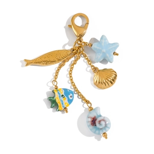 Détail d'un porte-clés marin avec breloques poissons dorés, étoiles de mer et coquillages