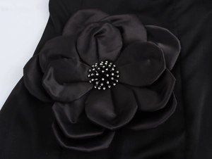 Dettaglio di un grande fiore 3D in raso nero con perline delicate su un abito da sera