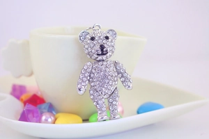 Close-up detail of a sparkling crystal-studded teddy bear pendant with black gemstone eyes