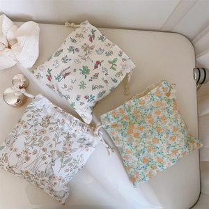 Détails de trois sacs de rangement en coton avec cordons et motifs floraux et lapins