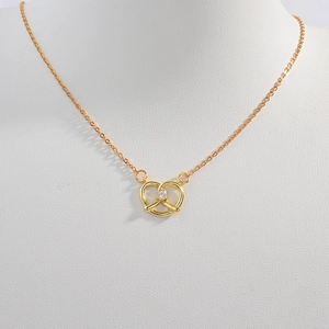 Élégant collier pretzel en argent S925 doré avec cristal étincelant sur buste blanc