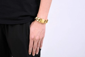 Detailed view of wide 20mm gold-plated Cuban chain bracelet on male wrist