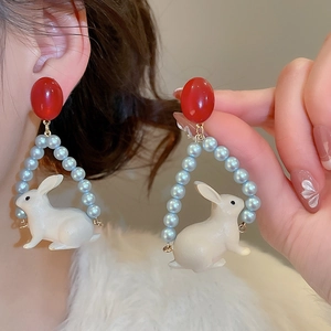 Détail des boucles d'oreilles lapin avec perles circulaires, haut rouge et design blanc