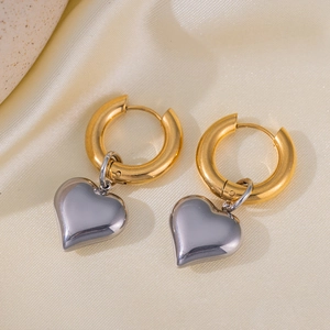 Detail of two-tone titanium steel earrings with heart charms on cream satin