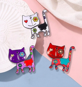 Detail of colorful enamel cat brooches with heart eyes on a stylish pastel background