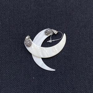 Macro detail of crescent moon pendants featuring white mother of pearl and dark gemstones
