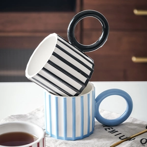 Creative striped ceramic mugs with circular handles stacked in a cozy kitchen setting
