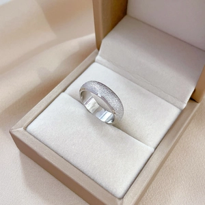 Macro shot of silver titanium steel ring with textured matte finish in a beige jewelry box
