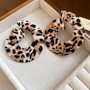 Detail of leopard print fabric round earrings on cream velvet jewelry display tray