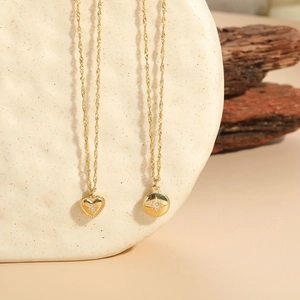 Close-up of gold heart and star pendants on textured stone with a natural wood background