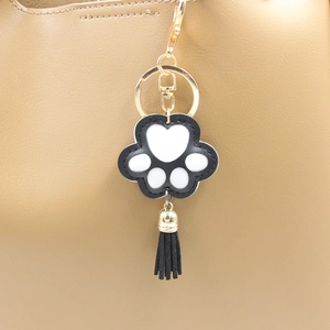 Porte-clés patte de chat en cuir PU noir avec pompon décoratif sur un sac en cuir marron