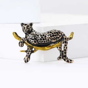Detail of leopard brooch on branch with black and gold enamel finish on white background