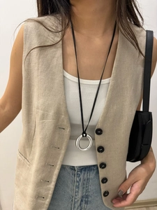 Close-up of minimalist silver mirror circle pendant on black leather cord necklace