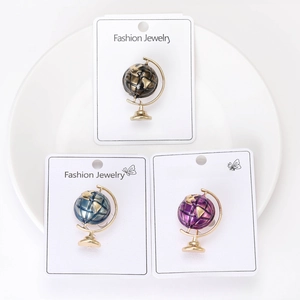 Close-up of alloy globe brooches in black, blue, and purple with gold plating detail