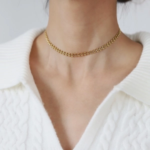 Macro shot of 18K gold plated wheat chain choker worn on a white knitted fabric background