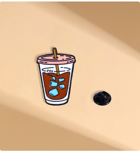 Macro view of a creative coffee cup enamel pin with blue ice cubes and black butterfly clutch