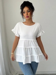 Detail of white pleated texture fabric with tiered layers and pompom tassel trim blouse