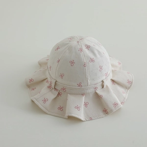 Detailansicht des cremefarbenen Baby-Sonnenhuts mit rosa Schleifen und Rüschenkrempe
