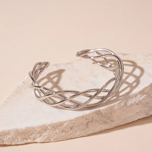 Macro detail of silver woven mesh cuff bracelet on a white textured stone base