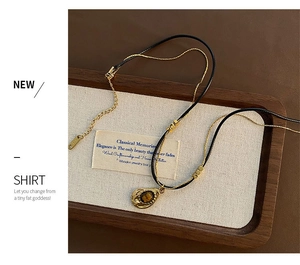 Detail of vintage double-layer necklace with golden tiger eye pendant on a wood tray