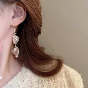 Primo piano di orecchini irregolari in madreperla con lucentezza naturale su una modella