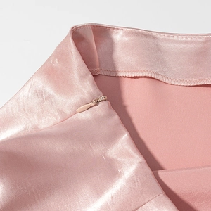 Détails de la fermeture éclair invisible sur le tissu satiné rose de la mini-jupe